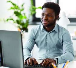 man smiling at desk with computer