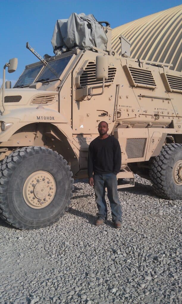 Spontaneous Poole, OFTC Welding Graduate, standing next to a military vehicle he'd performed maintenance on overseas. 