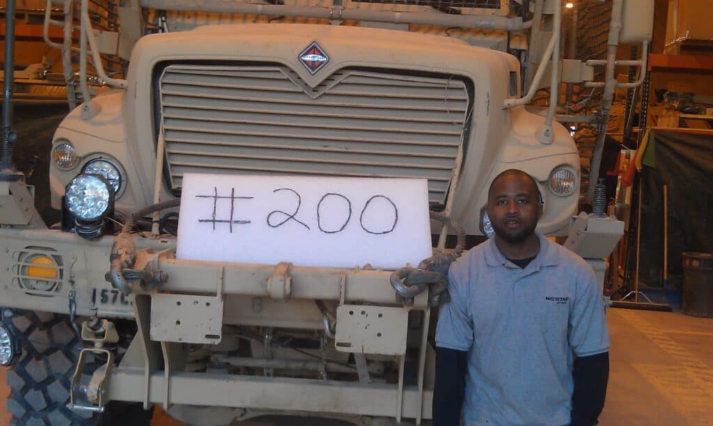 Spontaneous Poole, OFTC Welding Graduate, standing next to a military vehicle he'd performed maintenance on overseas. 