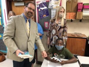 Bleckley County Superintendent, Steve Smith, handing out a Gifted Hands Book to a Bleckley County fifth grade student.