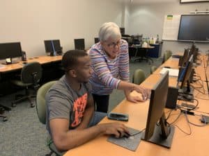 OFTC student in the tutoring lab at a computer receiving some instruction