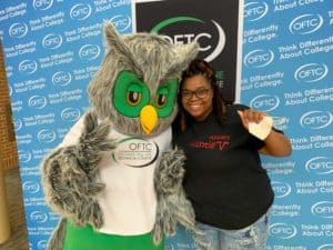 OFTC student smiling, standing with OFTC mascot Ollie